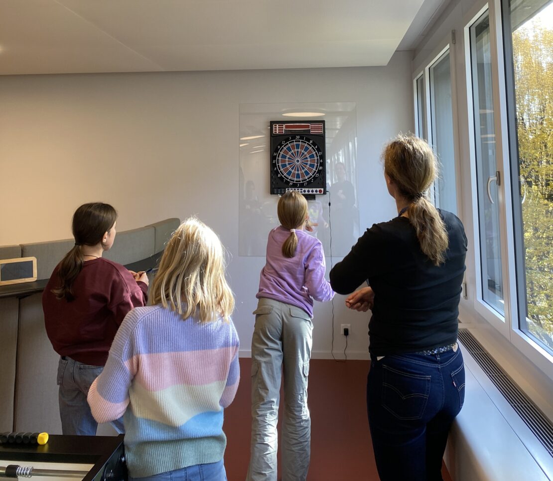 Die Schülerinnen sowie die Berufsbildende spielen Dart.